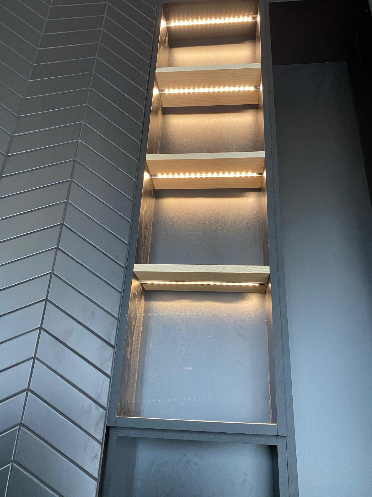 Vestavěná police s LED pásky v nikách a antracitovým rámem