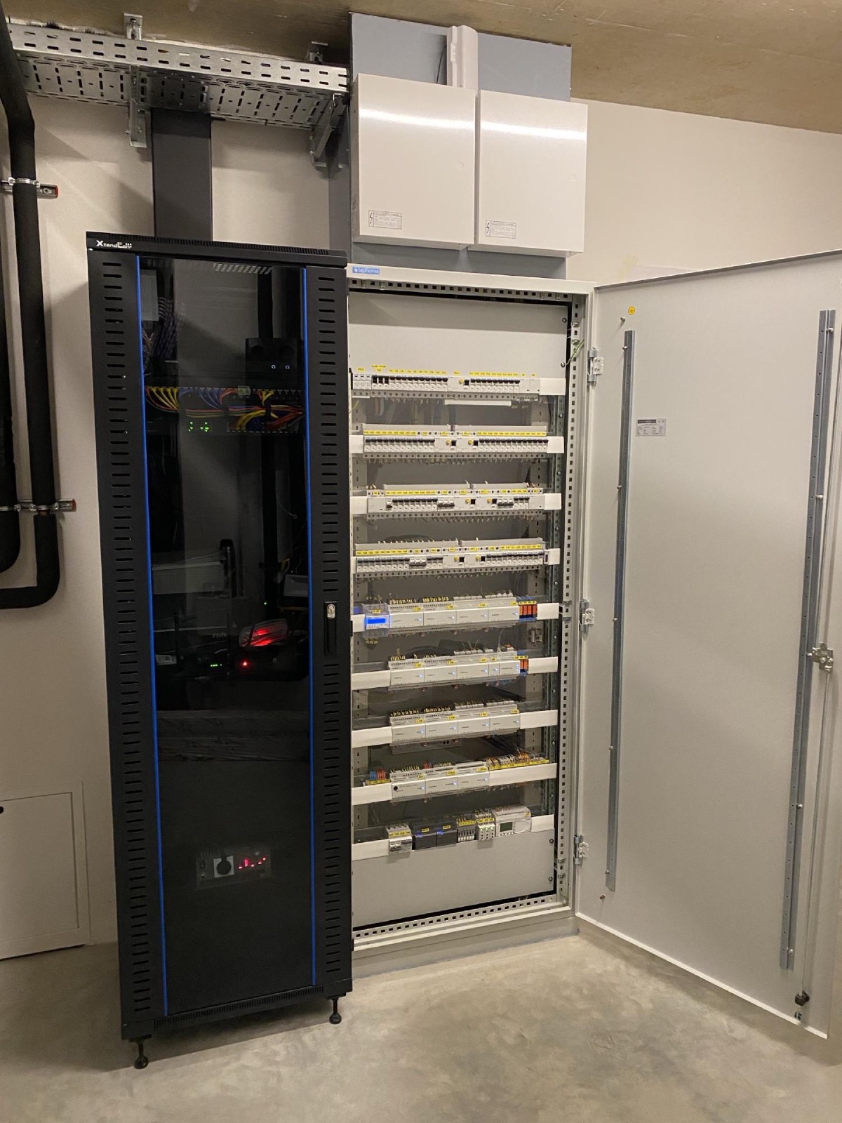 Technická místnost s otevřeným rozvaděčem TapHome a 19palcovým serverovým rackem