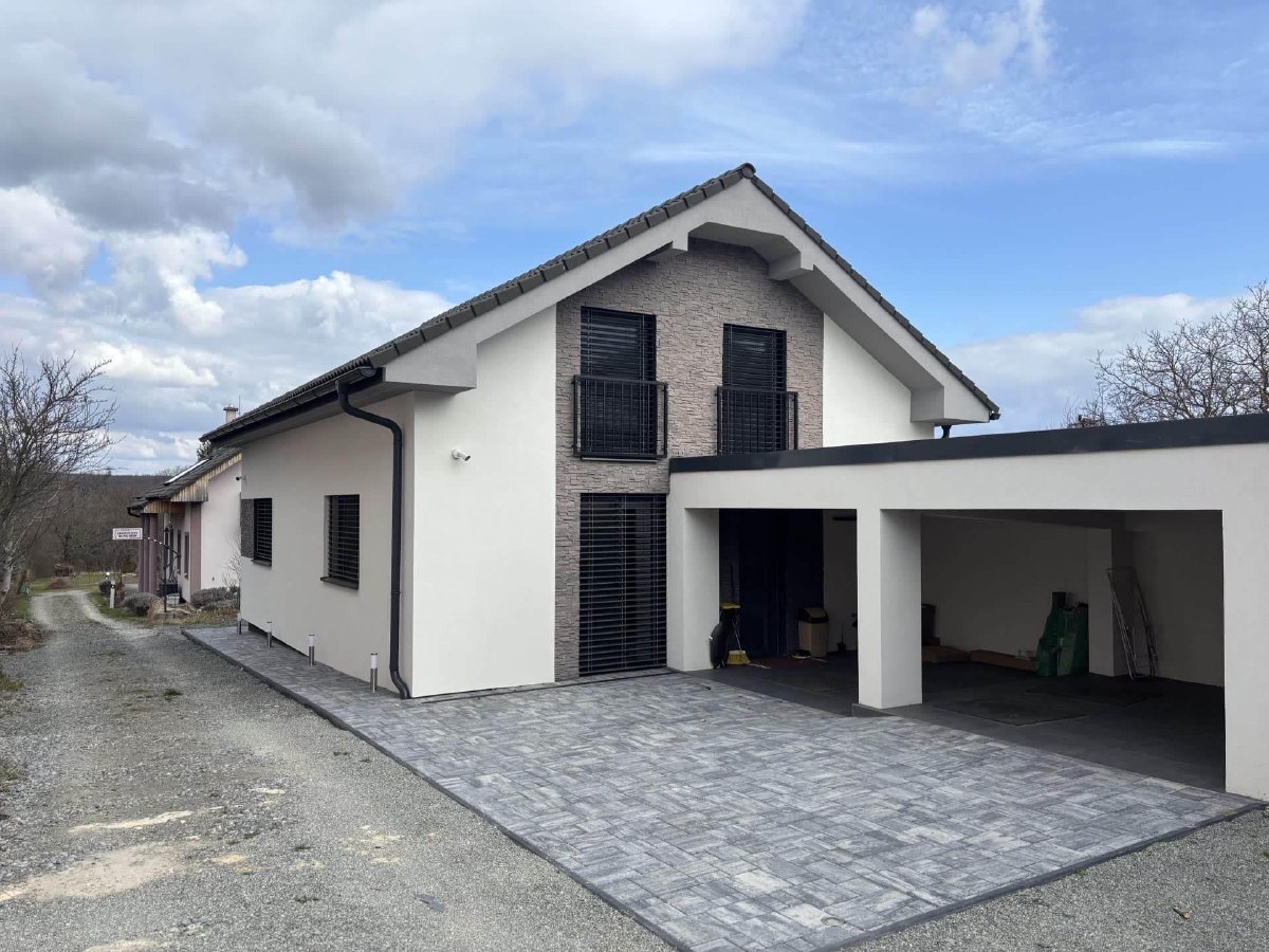 Nowoczesny dom jednorodzinny z dachem dwuspadowym i wiatą garażową, nowa zabudowa w Košickiej Novej Vsi — frontalny widok w ciągu dnia