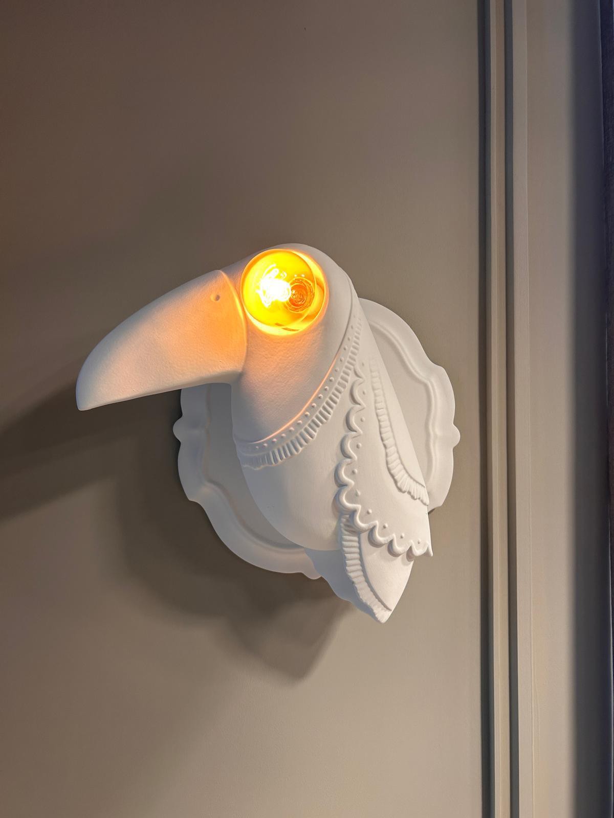 Decorative toucan-shaped wall sconce with warm Edison bulb