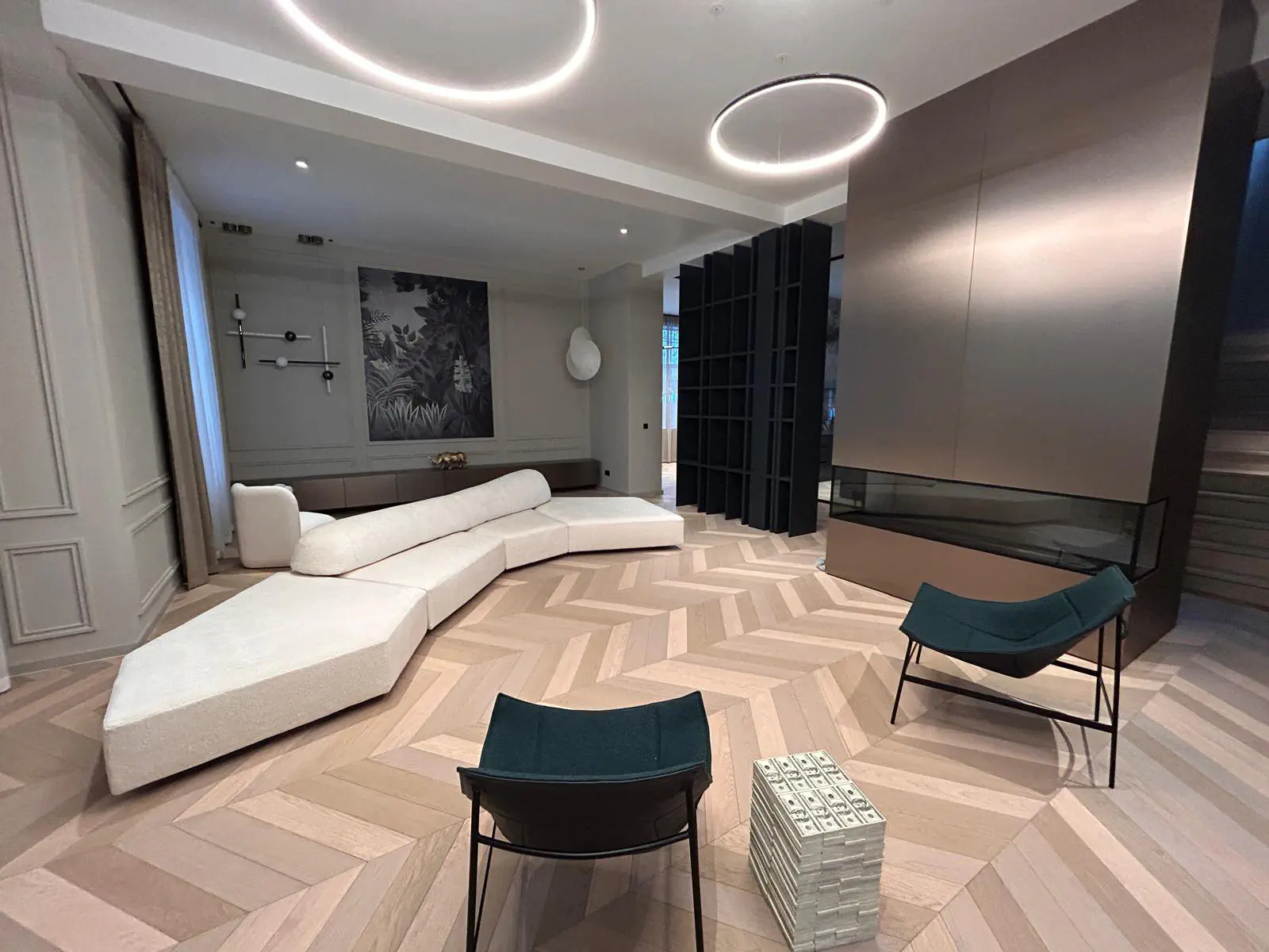 Living room with circular DALI ring LED ceiling lights, white curved sofa, and herringbone parquet floor in a Budapest luxury home